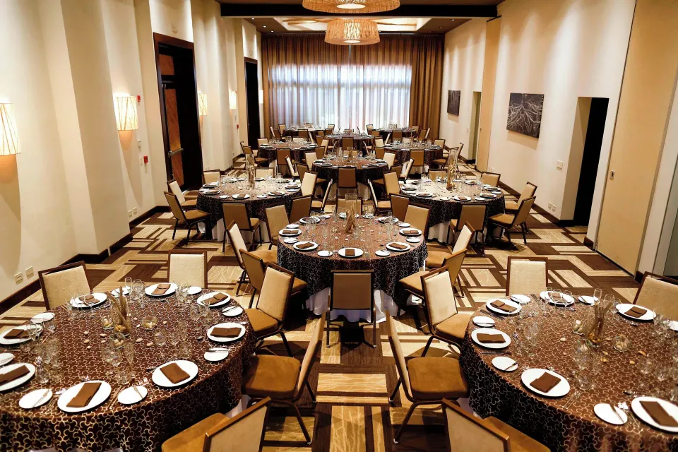 Indoor banquet room set with round dining tables at El Mangroove Papagayo