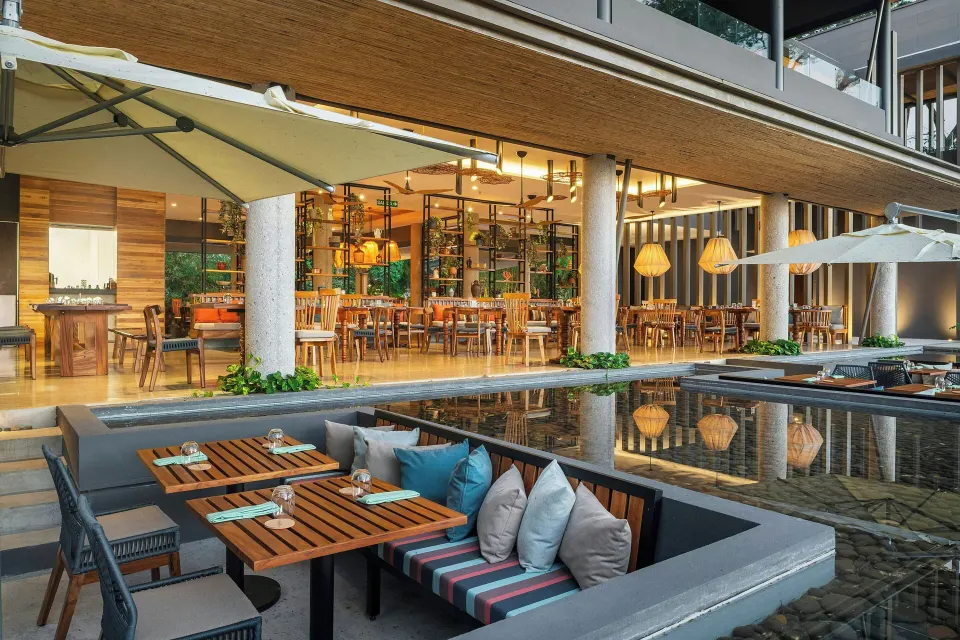 Outdoor recessed banquette dining beside reflecting pool at El Mangroove Papagayo