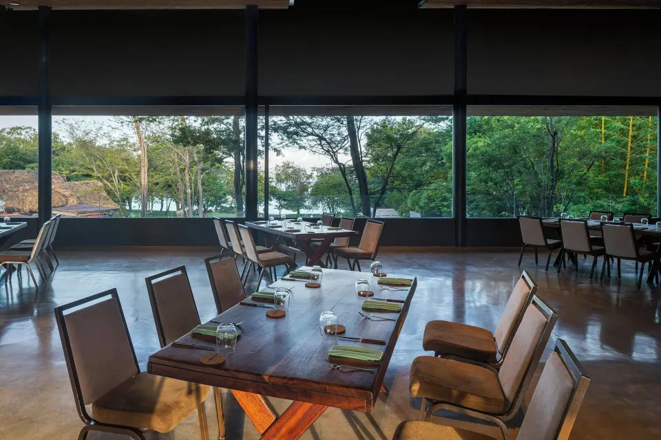Open dining room with tables and a water view at El Mangroove Papagayo