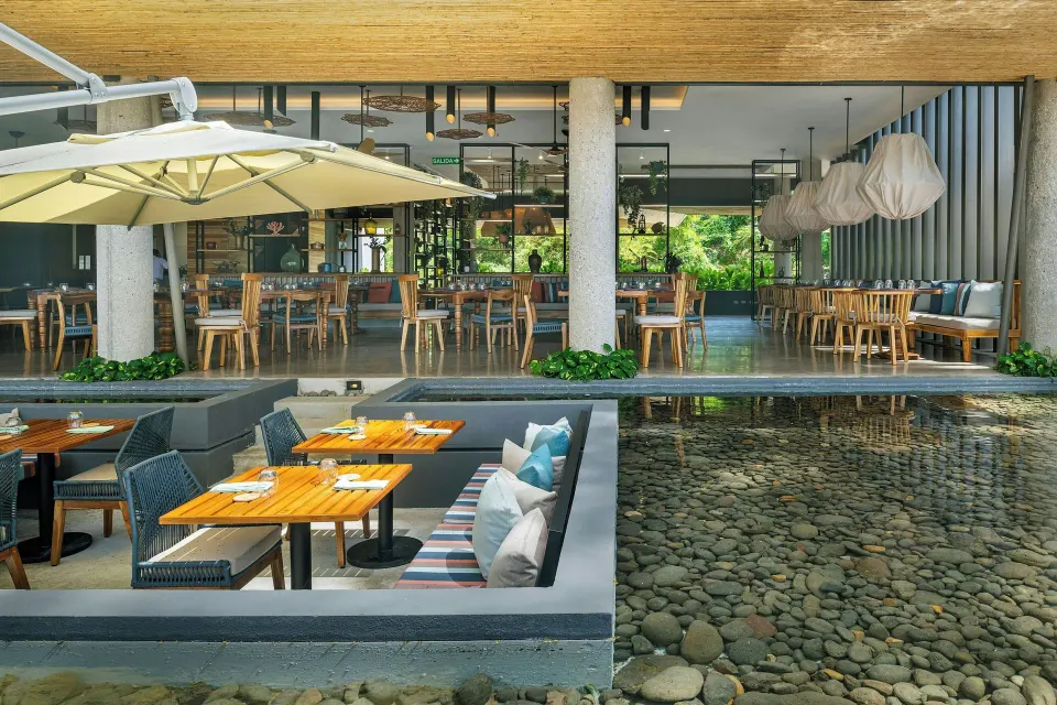 Sunken banquette seating adjacent to a shallow pebble water feature at El Mangroove Papagayo