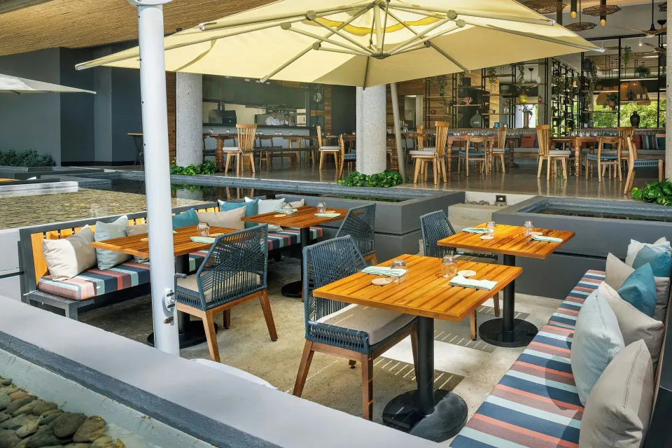 Sunken booth seating with umbrella-shaded tables near the restaurant at El Mangroove Papagayo