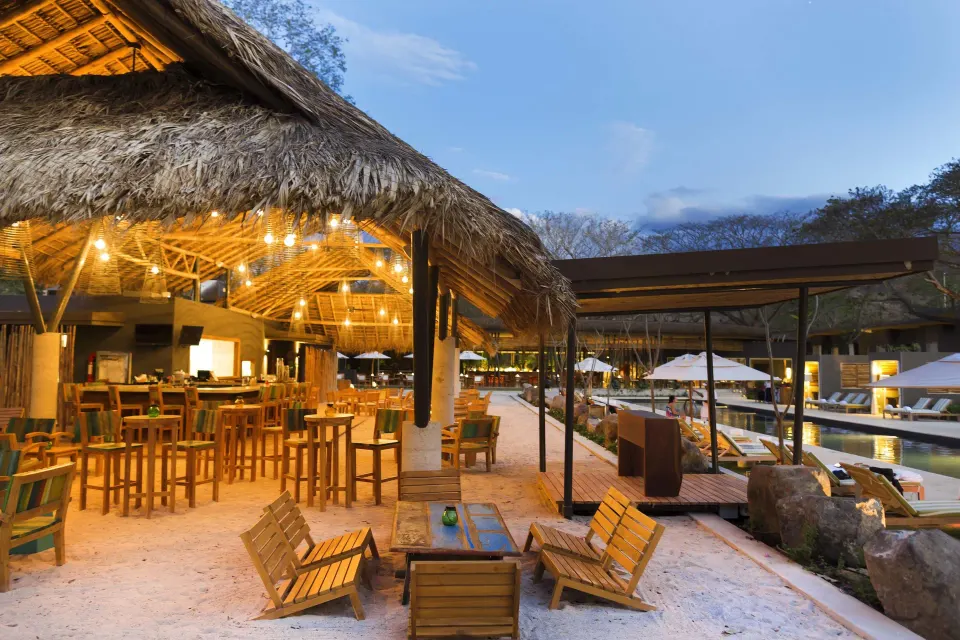 Thatched-roof beachfront bar and seating area at El Mangroove Papagayo