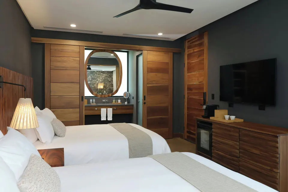 Guest bedroom with two twin beds and wood accents in a Balcony Garden villa at El Mangroove Papagayo