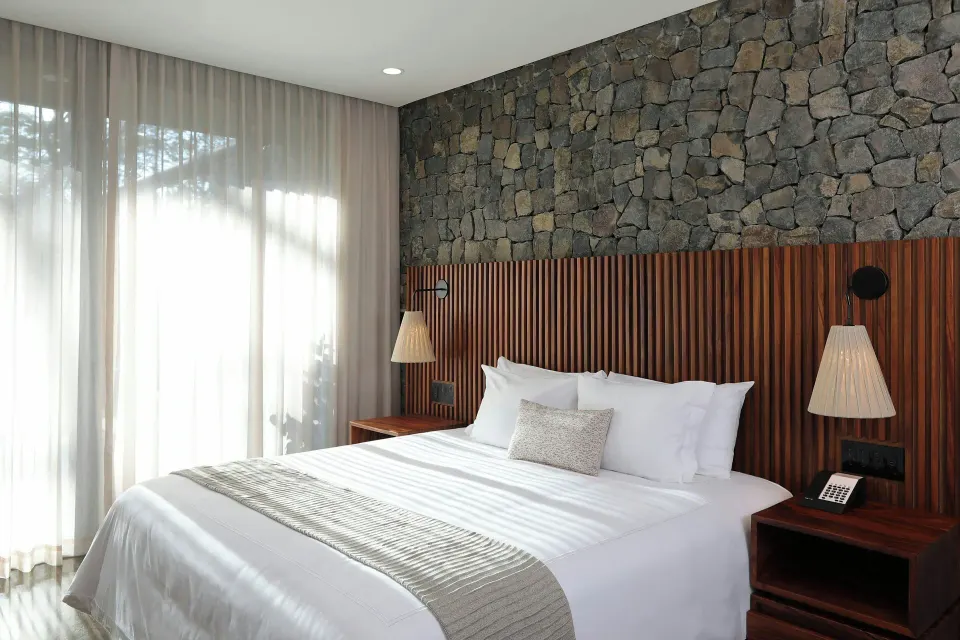 King bed against a stone wall in a Balcony Garden View Three-Bedroom Villa at El Mangroove Papagayo