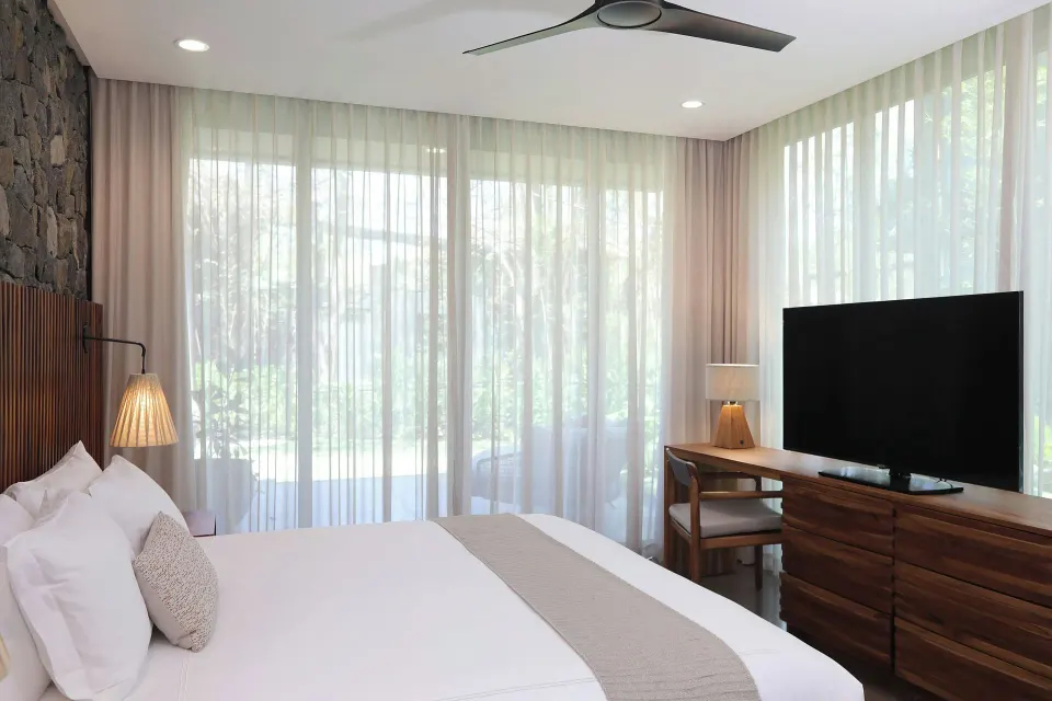 King bed and large TV with floor-to-ceiling curtains in a Balcony Garden View Three-Bedroom Villa at El Mangroove Papagayo