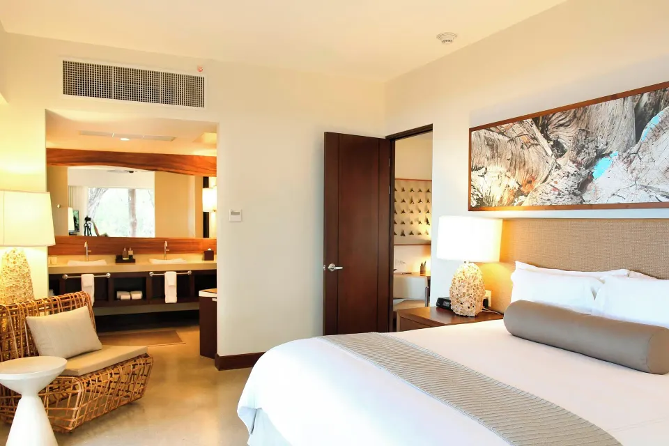 King bed and bedside lamp in a Presidential Suite with bathroom entrance at El Mangroove Papagayo