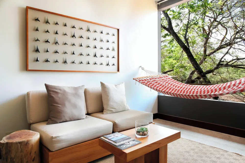 Resort View Suite balcony lounge with sofa, coffee table and hammock at El Mangroove Papagayo