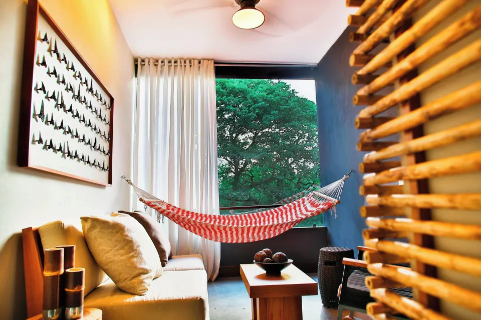 Resort View Suite seating area with hammock and tree-framed window at El Mangroove Papagayo