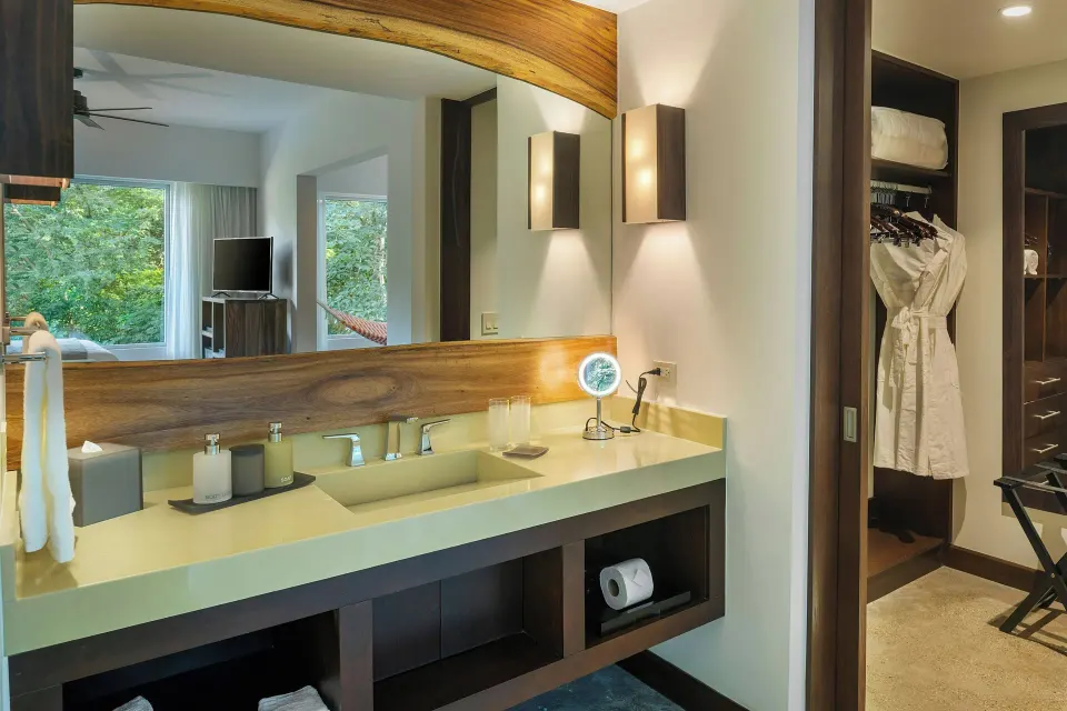 Bathroom sink and mirror with robe and closet entry seen from a suite at El Mangroove Papagayo