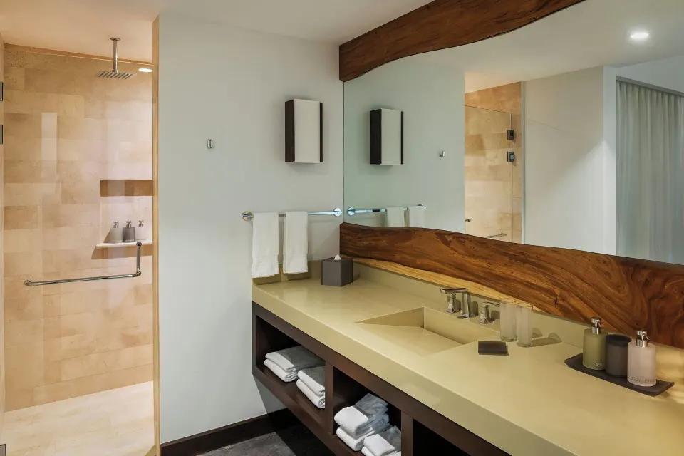 Bathroom counter with toiletries and stacked towels in a suite at El Mangroove Papagayo