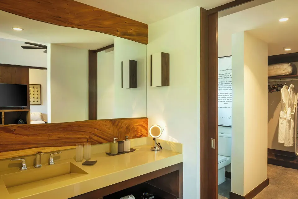 Bathroom vanity and mirror with wood accents in a suite at El Mangroove Papagayo