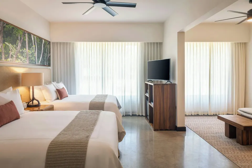 Suite with two beds, TV cabinet and abundant natural light at El Mangroove Papagayo