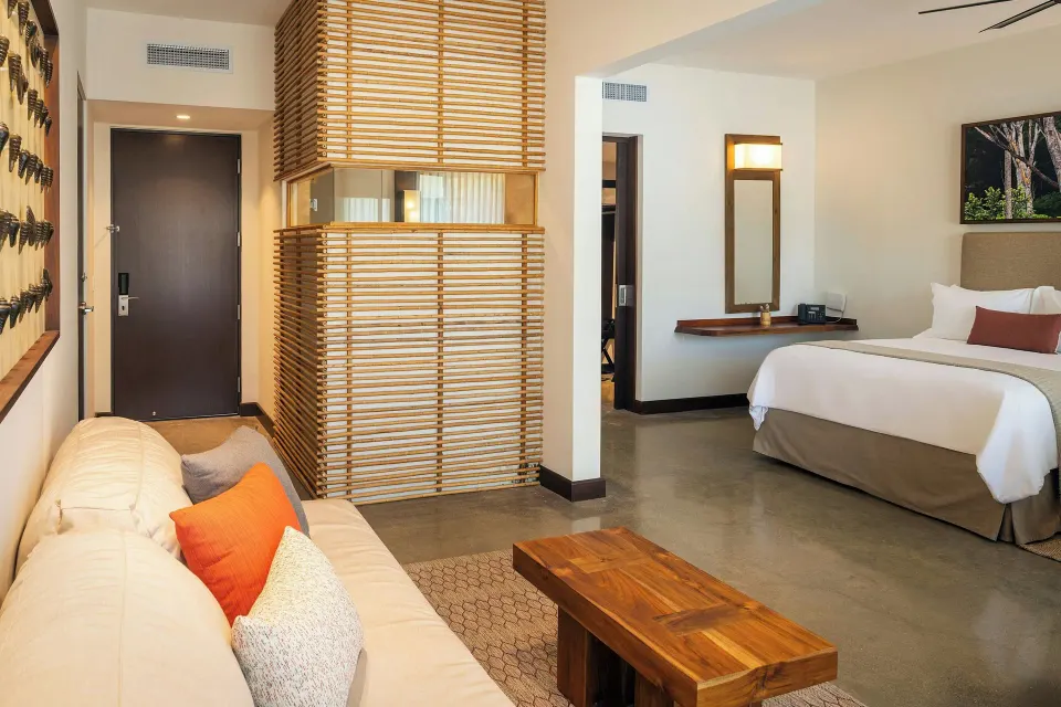 Suite entry showing sofa, wooden partition and one queen bed at El Mangroove Papagayo