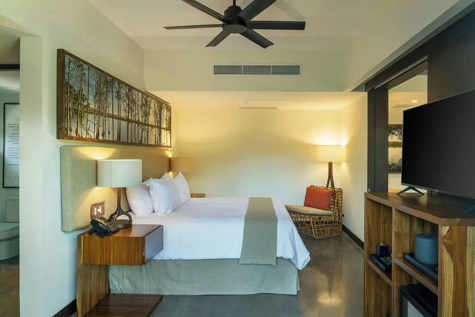 King bed and bedside tables in a suite at El Mangroove Papagayo with ceiling fan