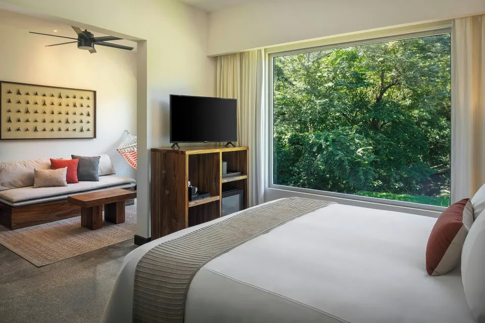 King bed and large picture window overlooking greenery in a suite at El Mangroove Papagayo
