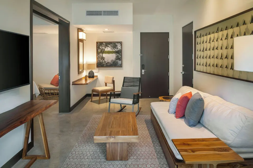 Suite sitting room with sofa, desk and doorway into sleeping area at El Mangroove Papagayo
