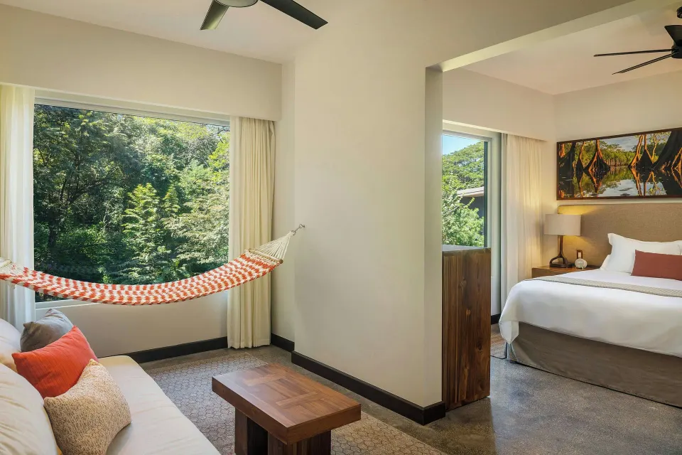 Living area with hammock and sofa adjoining a bedroom in a suite at El Mangroove Papagayo