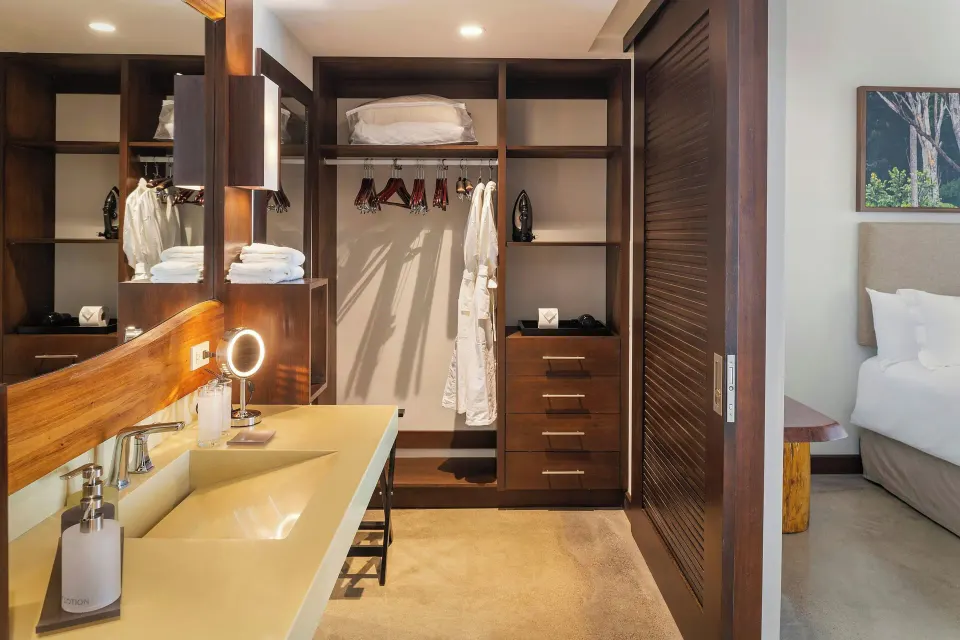 Open wardrobe and vanity area with hanging robes and shelves in a suite at El Mangroove Papagayo