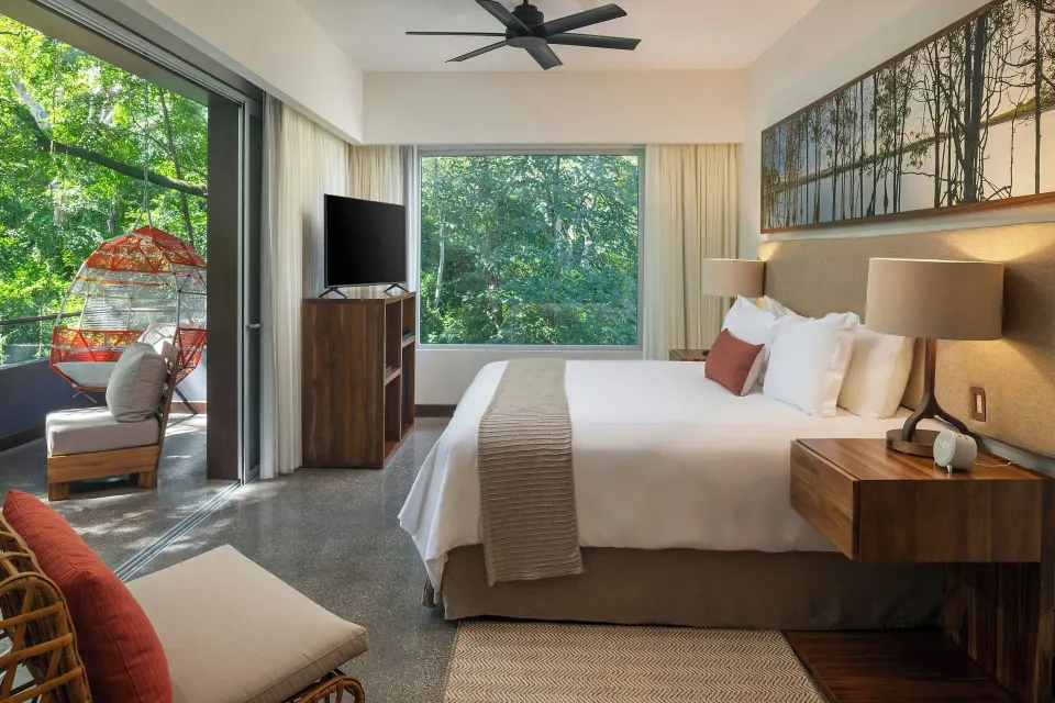 Superior Balcony One-Bedroom Suite king bed and balcony with hanging chair at El Mangroove Papagayo