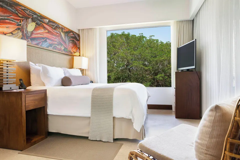 Superior One‑Bedroom Suite king bed and window view of mangroves at El Mangroove Papagayo