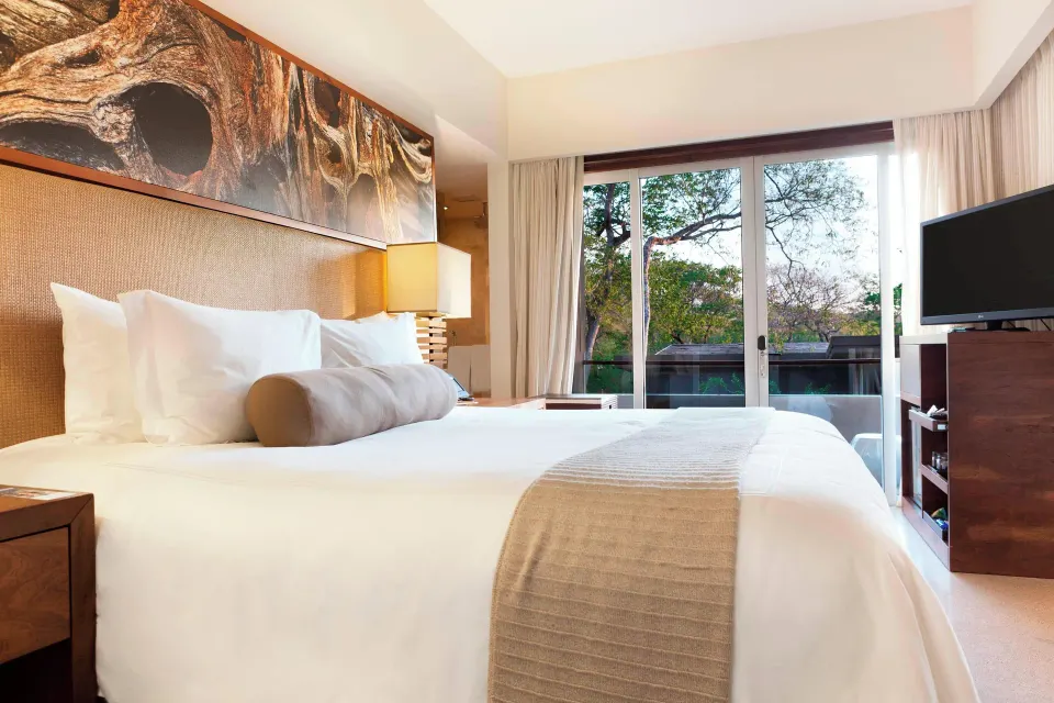King bed and sliding balcony doors in a Resort View Junior Suite at El Mangroove Papagayo