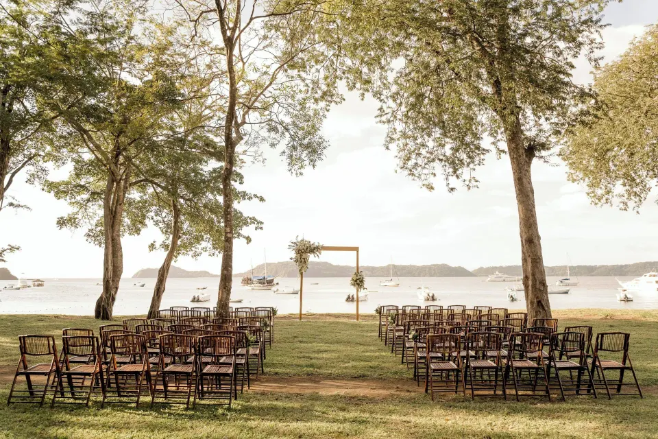 Rows of chairs set on the beachfront facing a floral arch at El Mangroove Papagayo