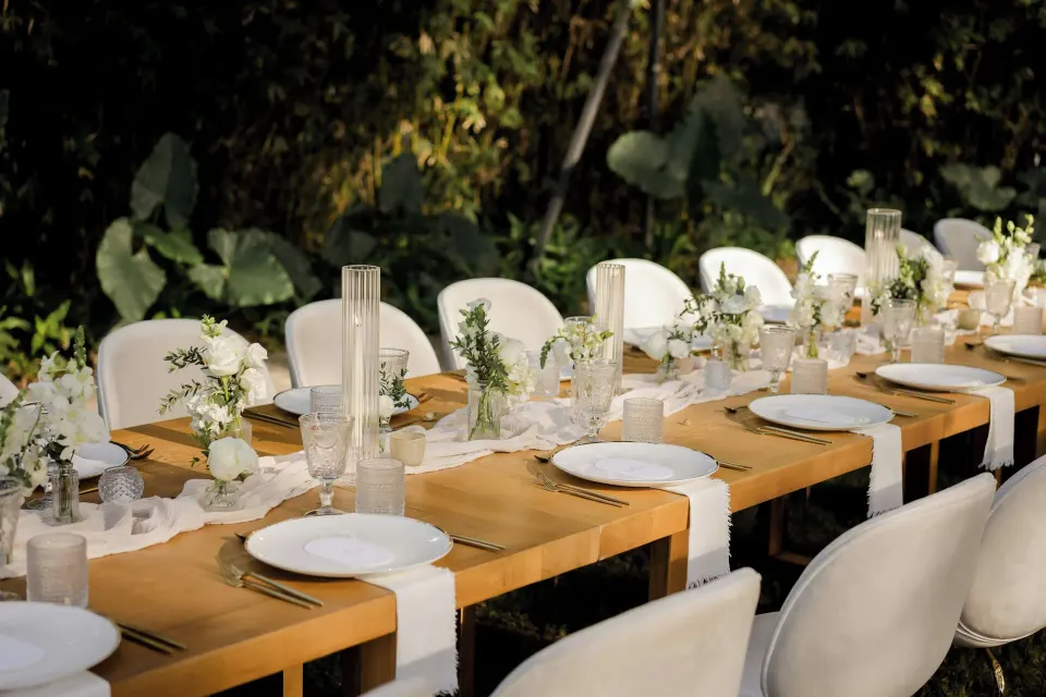 Long wooden table with white plates and floral runners at El Mangroove Papagayo