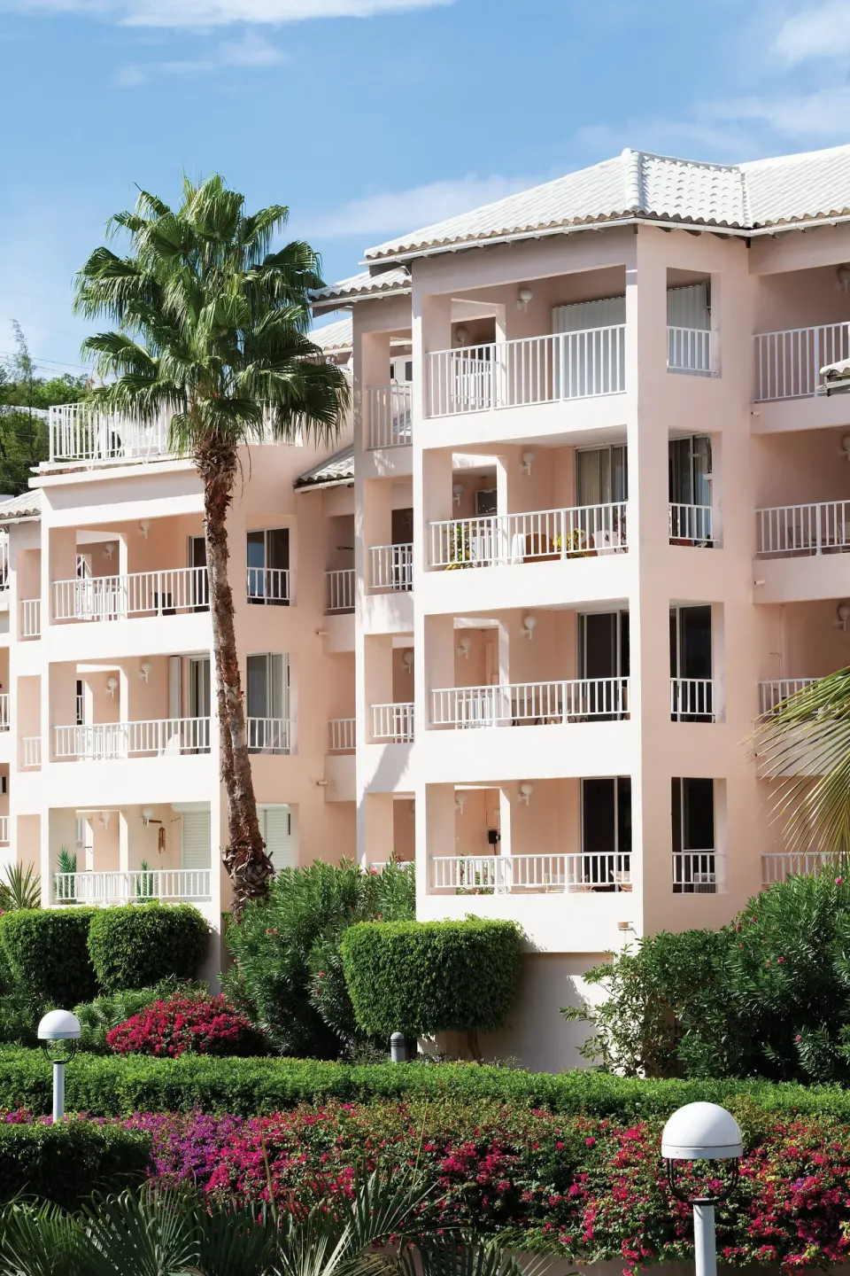 Pink resort building with balconies and tropical gardens at Elysian Beach Resort.