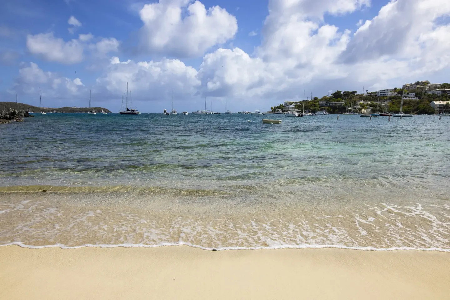 Sandy beach and blue bay with anchored boats at Elysian Beach Resort.