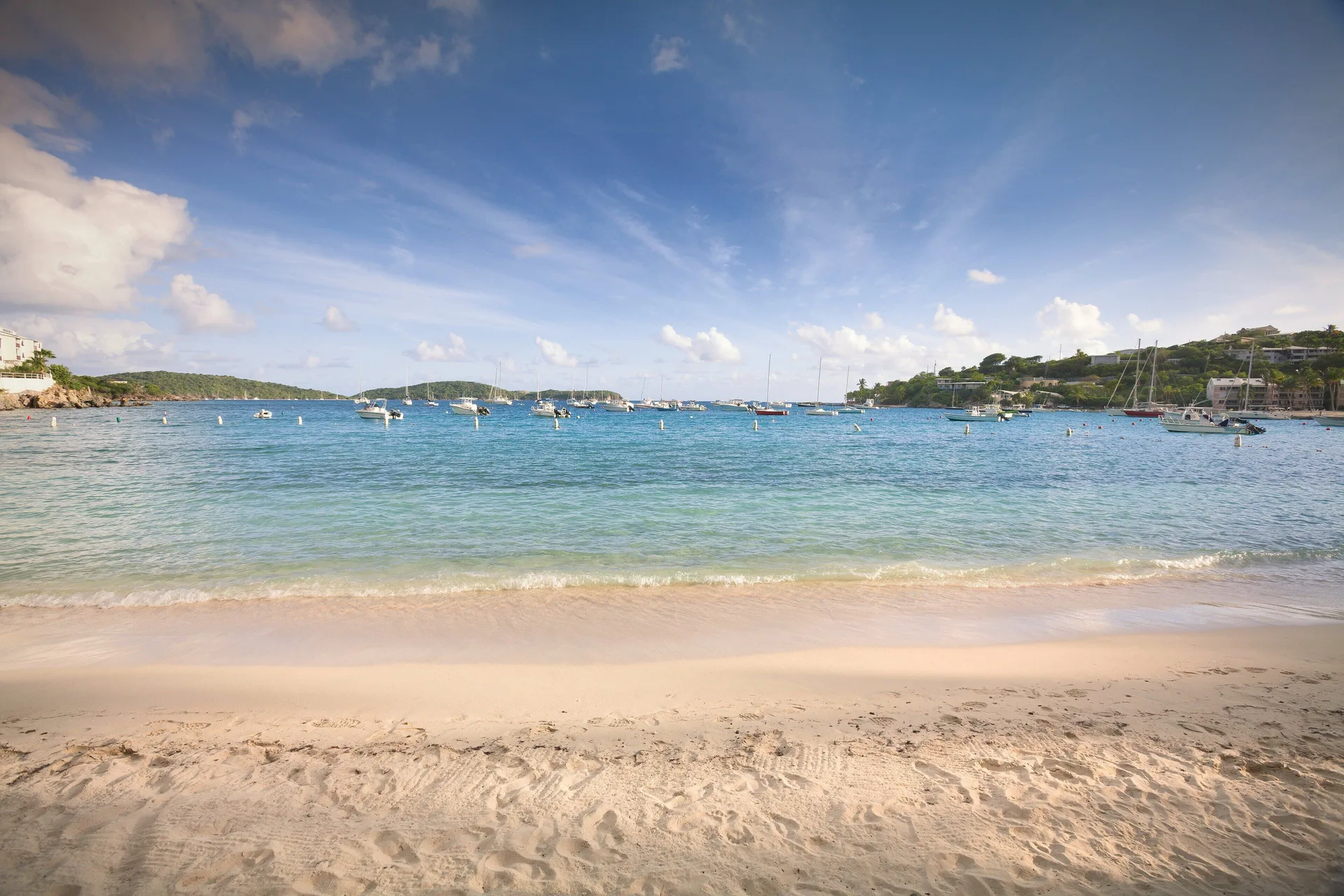Sandy beach and clear bay with anchored boats at Elysian Beach Resort.