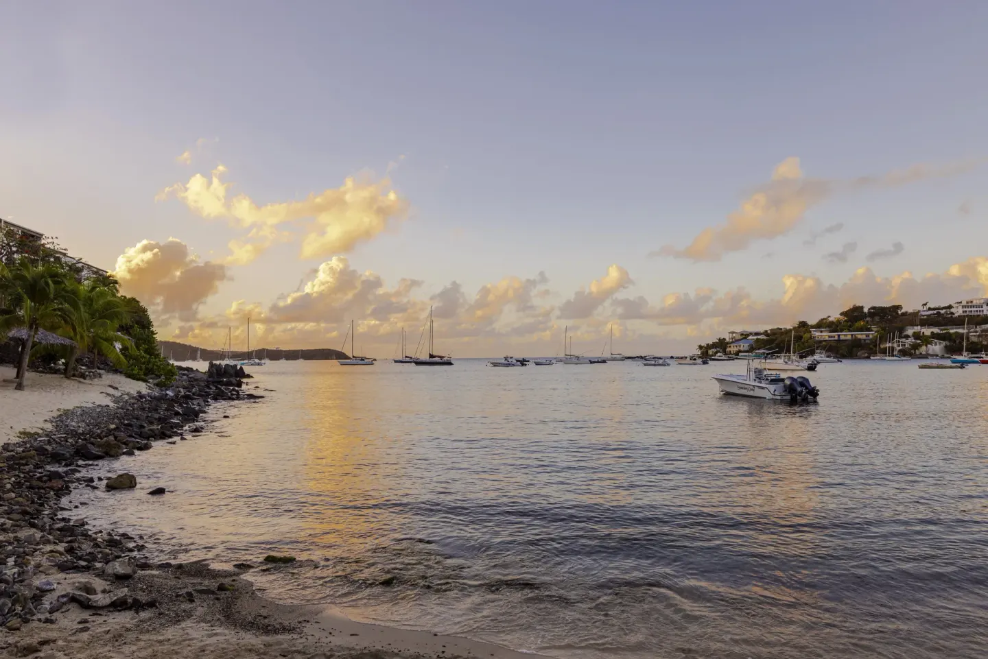 Evening bay view with anchored boats and rocky shoreline at Elysian Beach Resort.