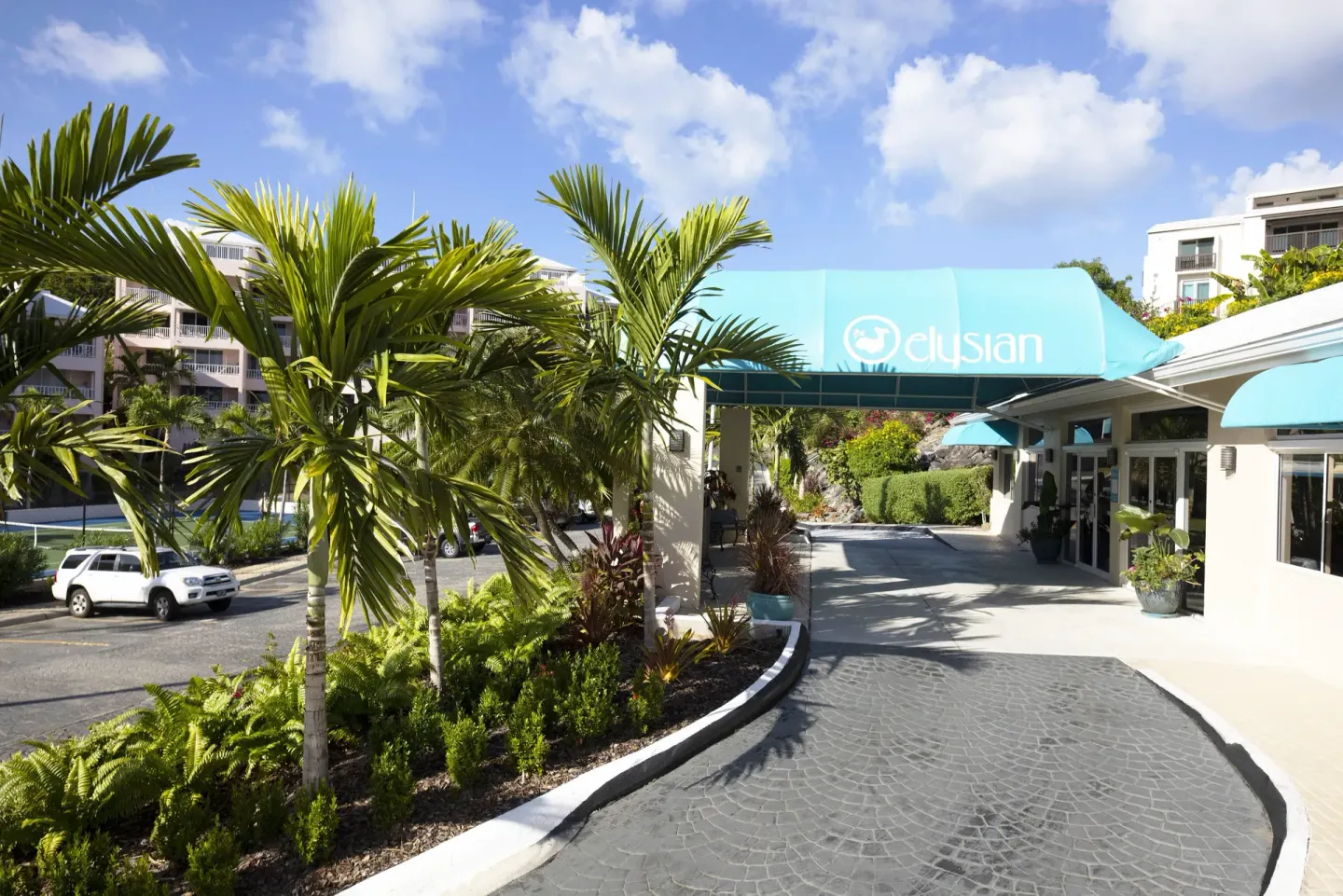 Palm-lined entrance canopy and driveway at Elysian Beach Resort.