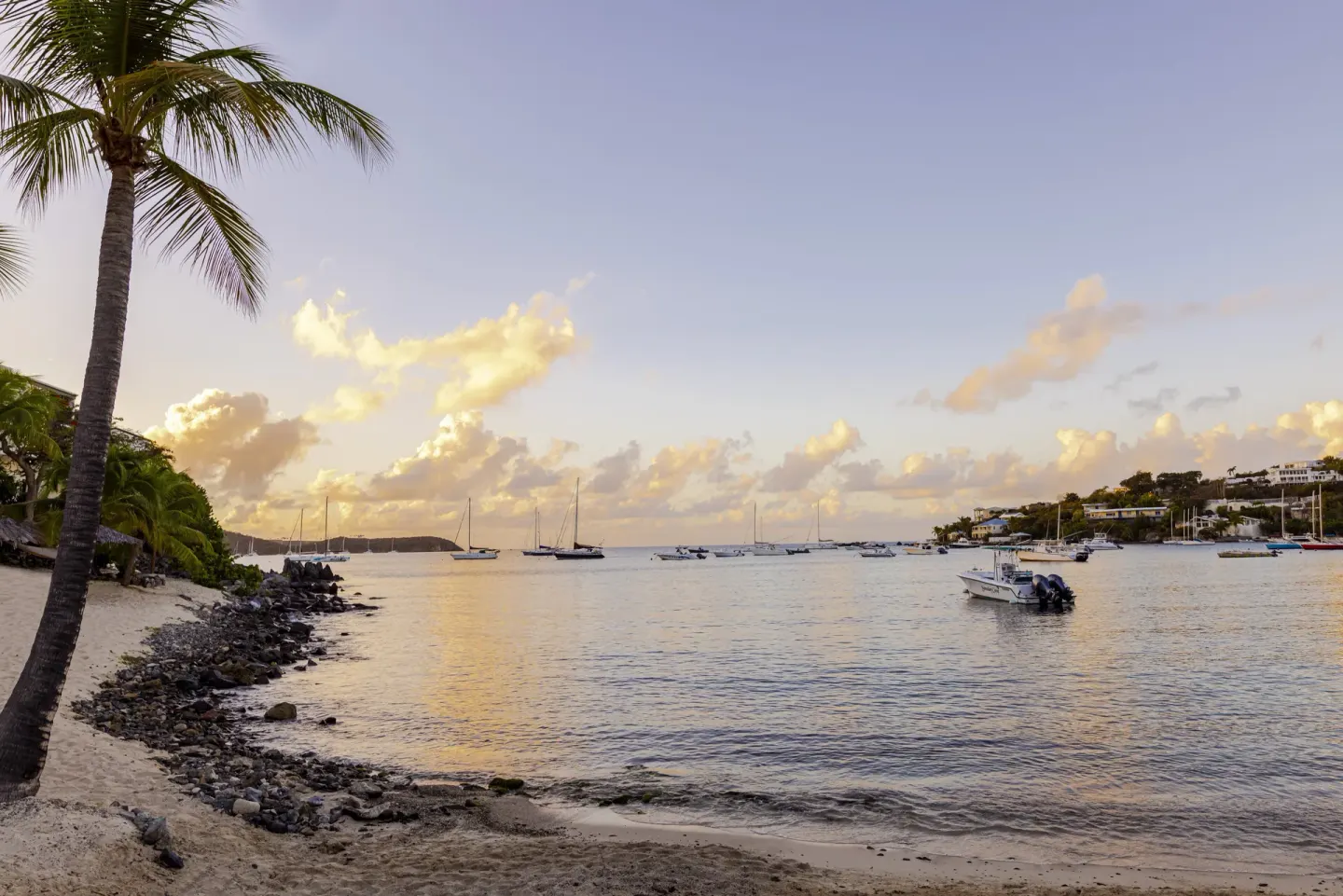 Calm bay at sunset with boats and a palm-lined shoreline at Elysian Beach Resort.