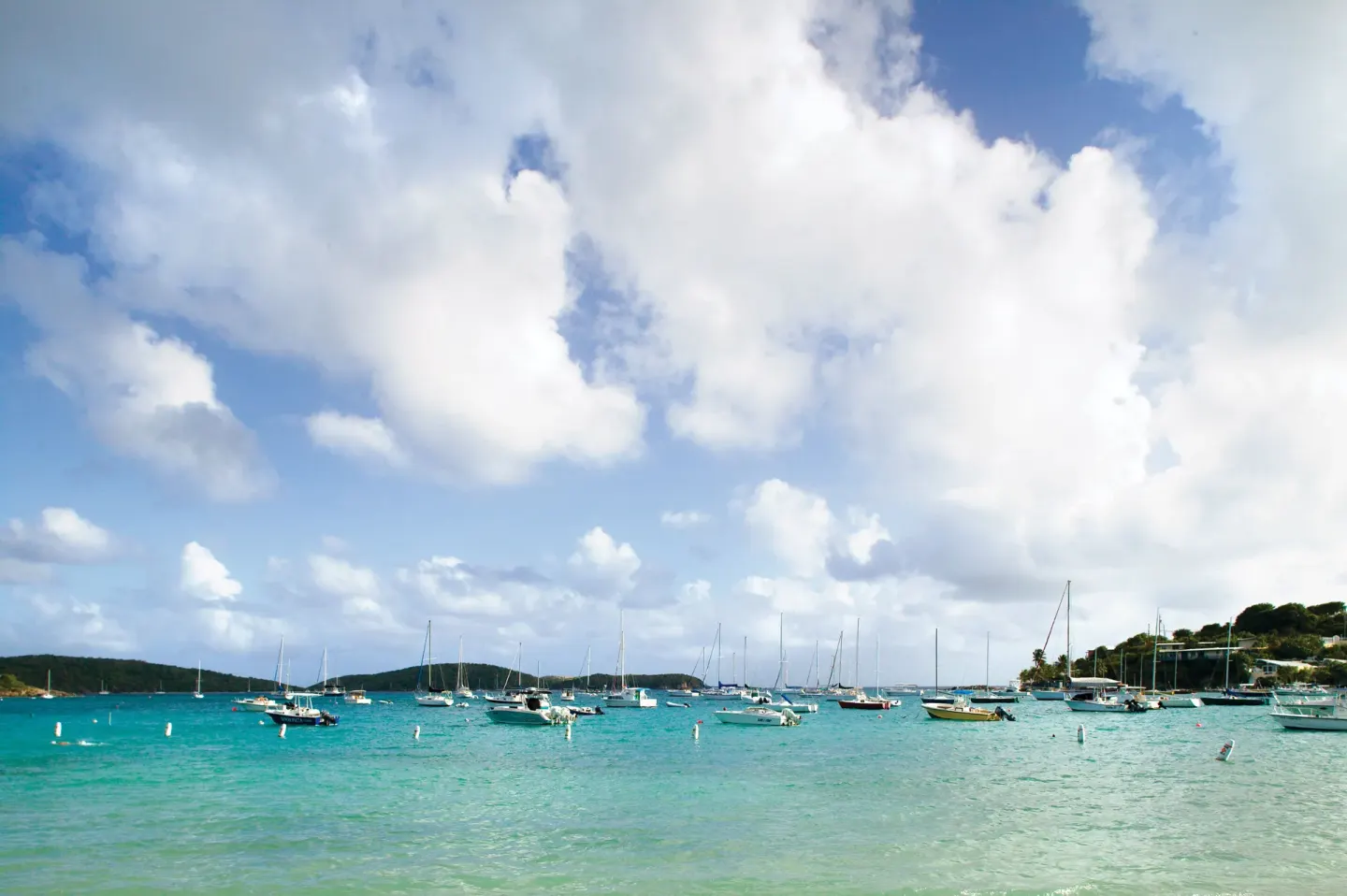 Turquoise bay with sailboats under large clouds at Elysian Beach Resort.