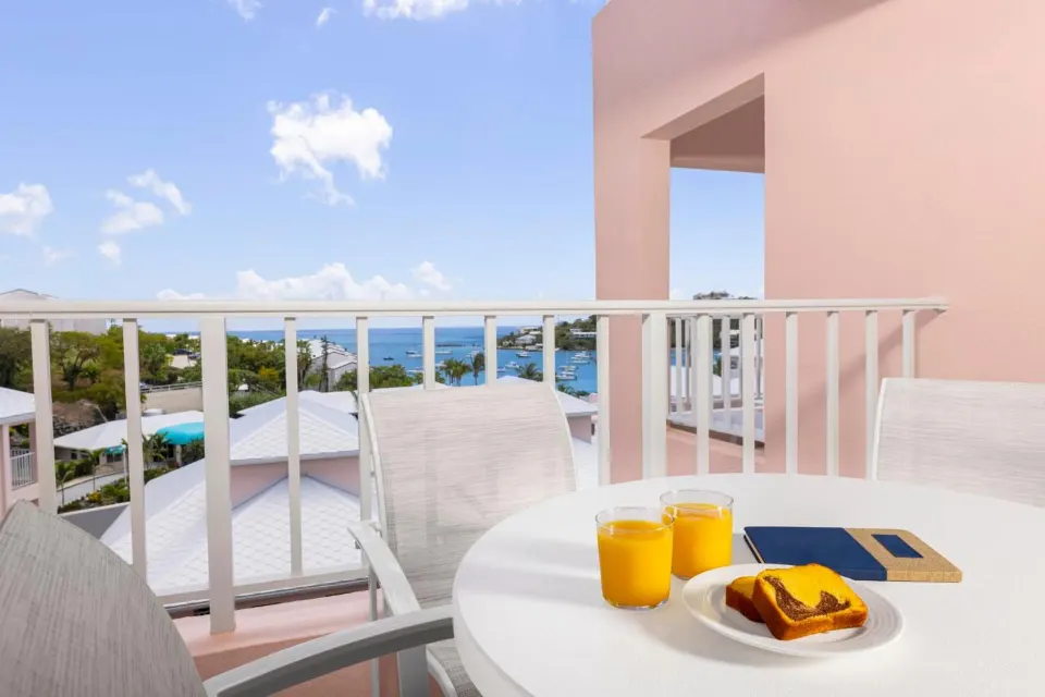 Studio parlor suite balcony with table, chairs and ocean view at Elysian Beach Resort.