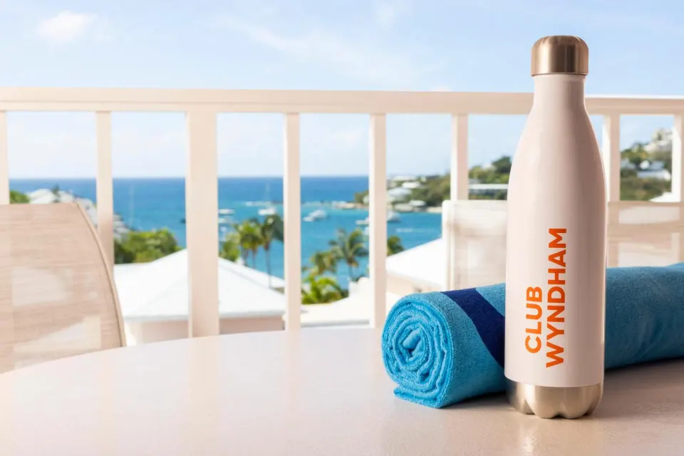 Studio parlor suite balcony table with towel and bottle at Elysian Beach Resort.