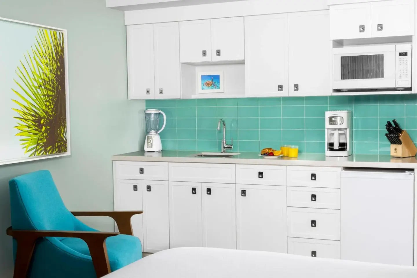 Studio parlor suite kitchenette with white cabinetry and turquoise tile at Elysian Beach Resort.