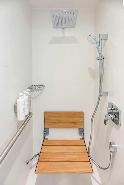 Accessible shower with bench and handheld sprayer at Embassy Suites Aruba Beach Resort.
