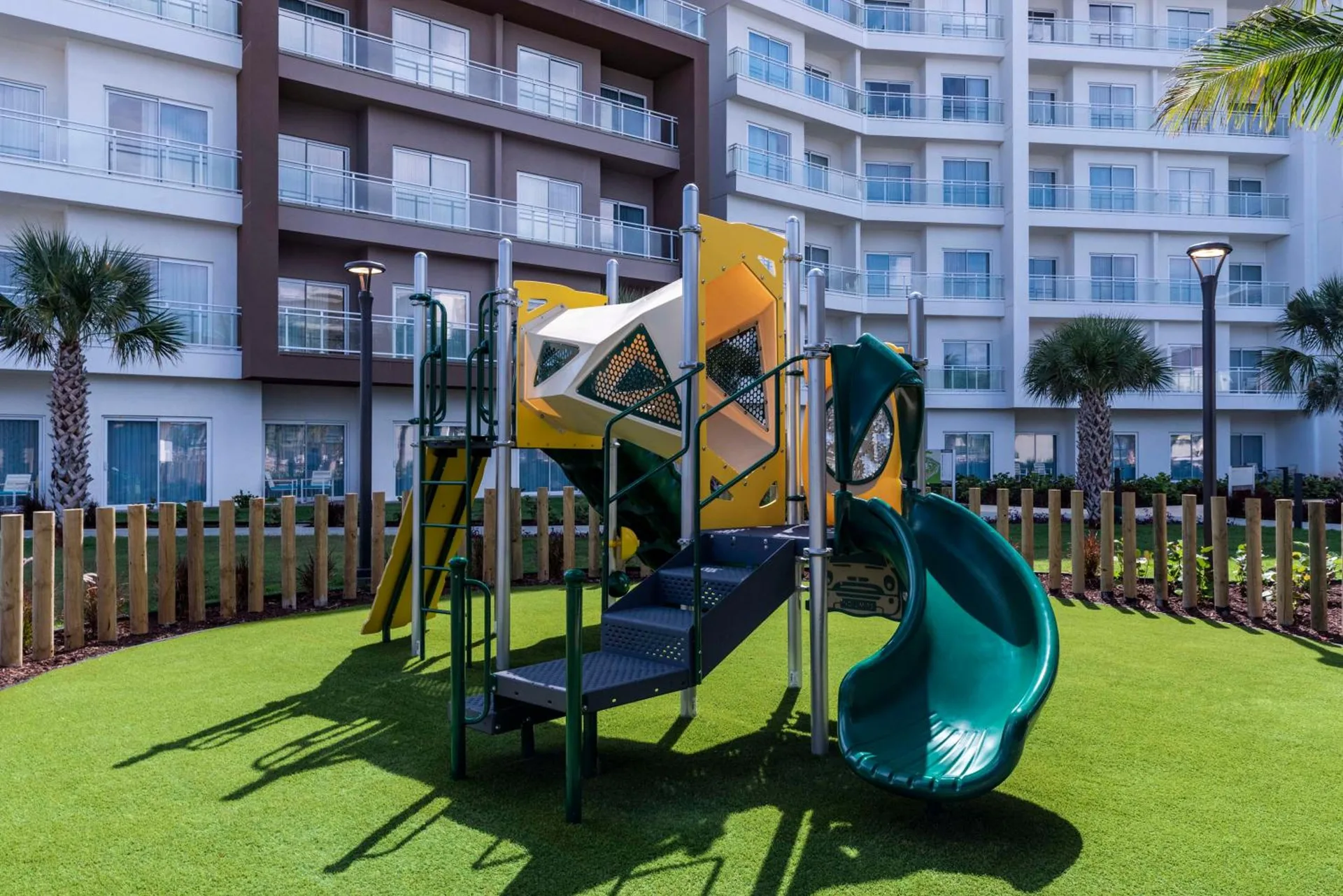 Children's playground with slide on turf at Embassy Suites Aruba Beach Resort.