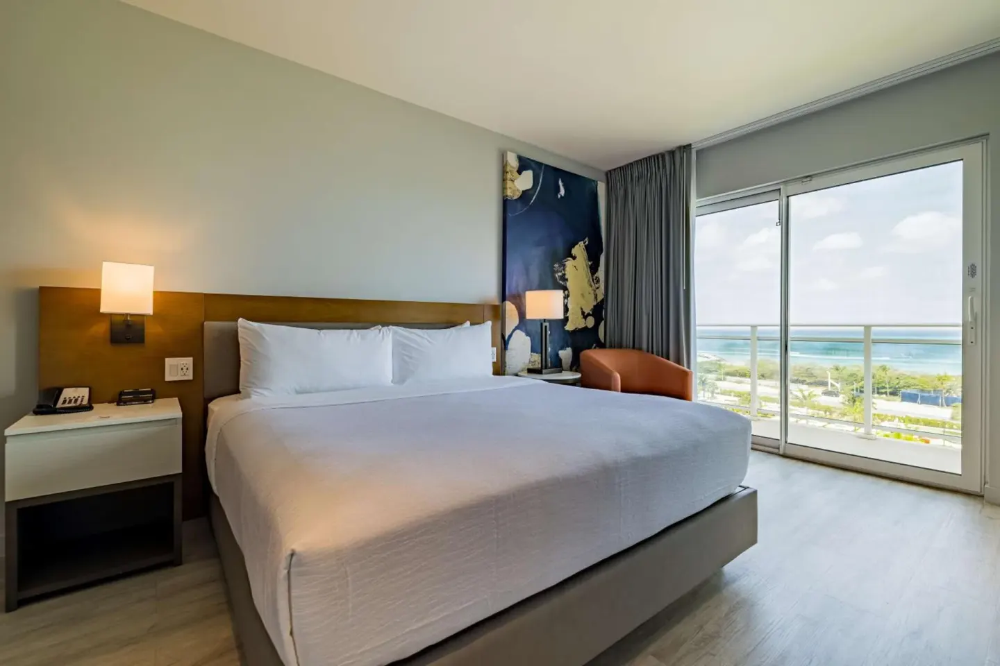 King guest room with balcony and ocean view at Embassy Suites Aruba Beach Resort.