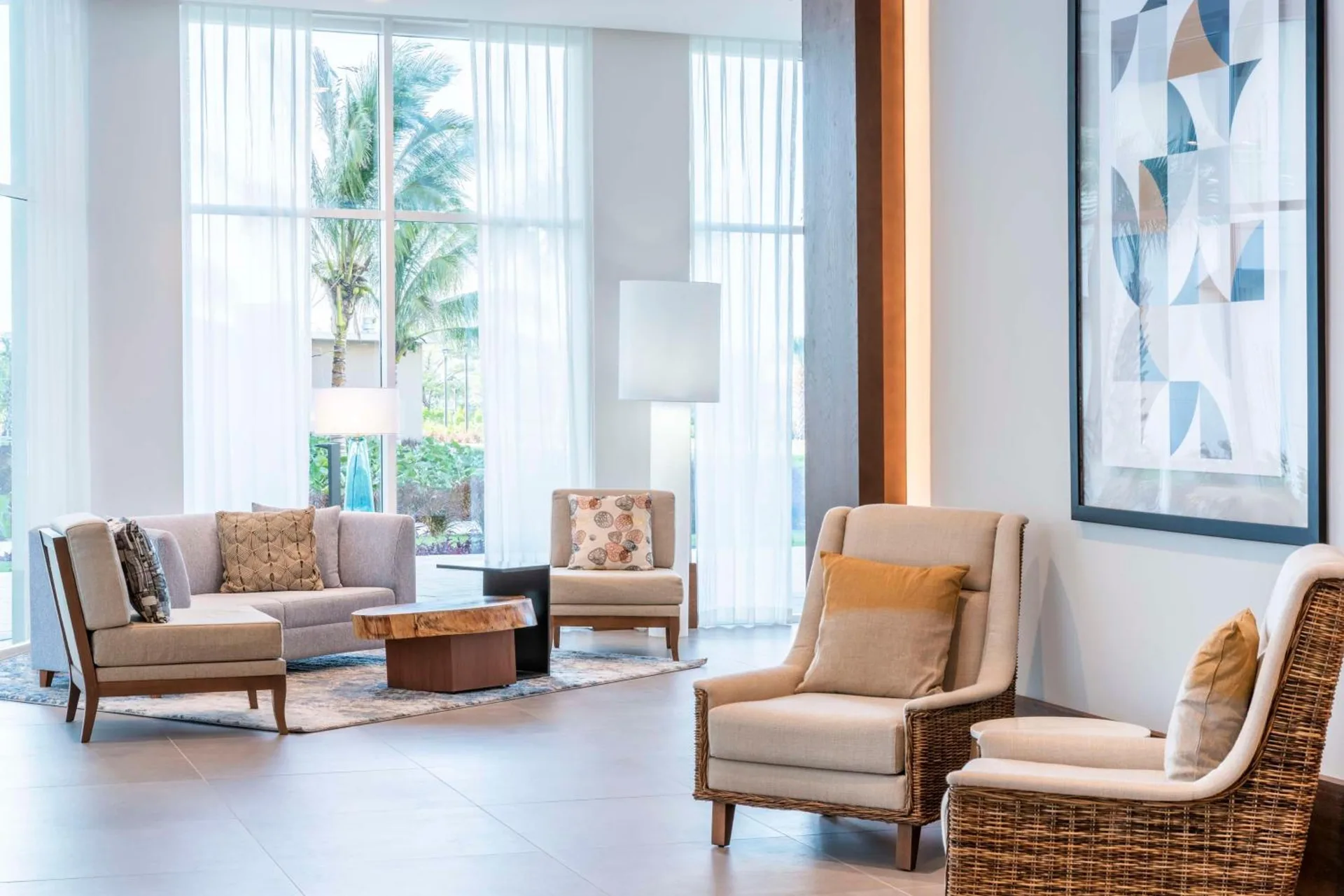 Lobby lounge seating with tall windows at Embassy Suites Aruba Beach Resort.