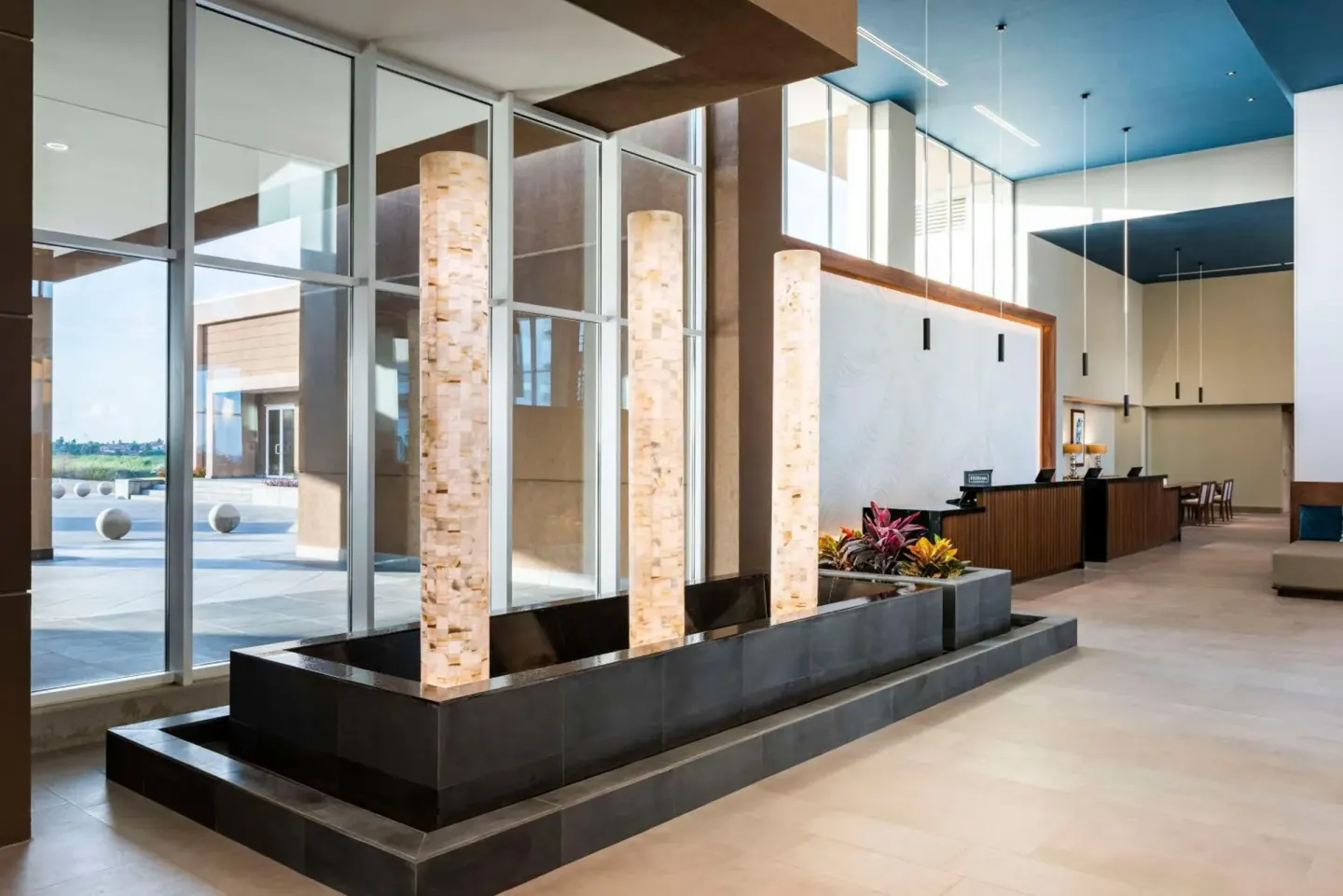 Lobby water feature with tall stone light columns at Embassy Suites Aruba Beach Resort.
