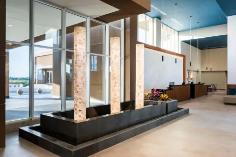 Lobby water feature with tall stone light columns at Embassy Suites Aruba Beach Resort.