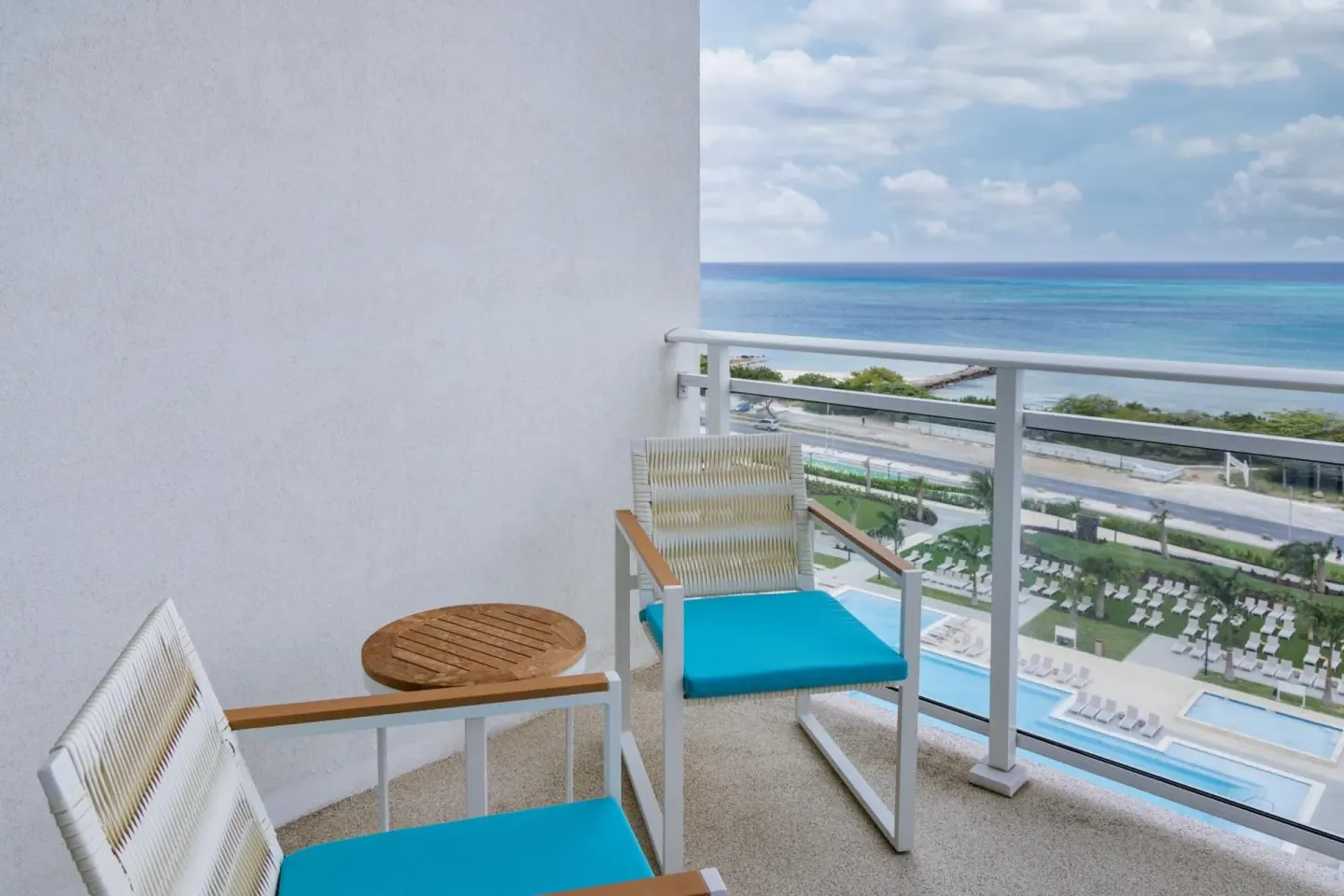 Balcony seating with ocean and pool views at Embassy Suites Aruba Beach Resort.