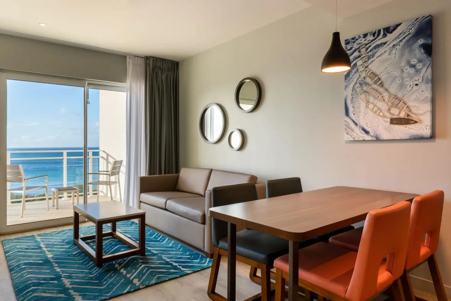Ocean-view suite living area with sofa and dining table at Embassy Suites Aruba Beach Resort.