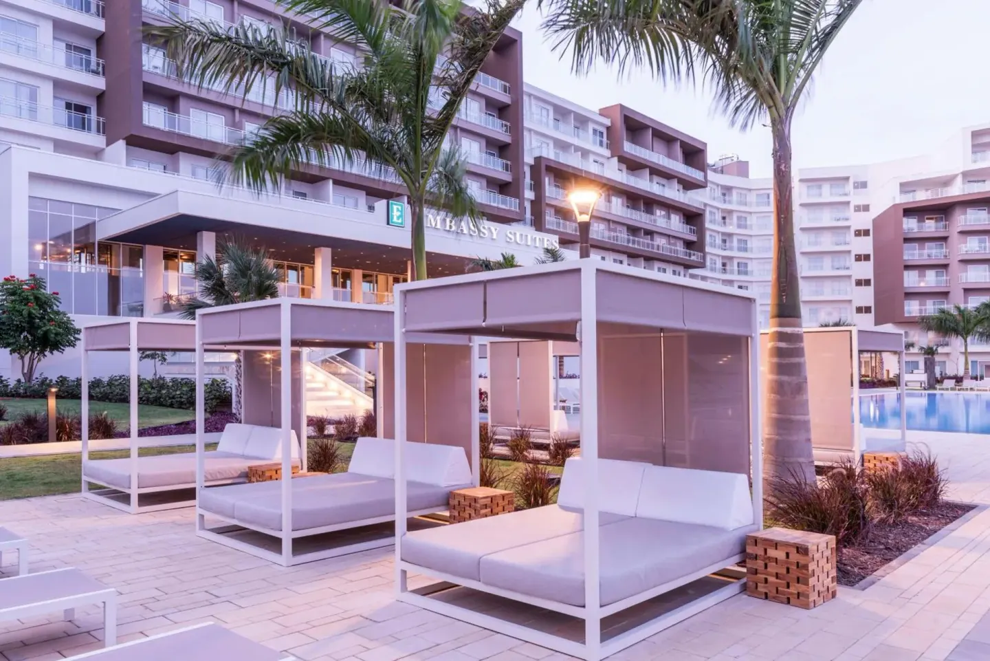 Poolside cabanas and resort building at Embassy Suites Aruba Beach Resort.