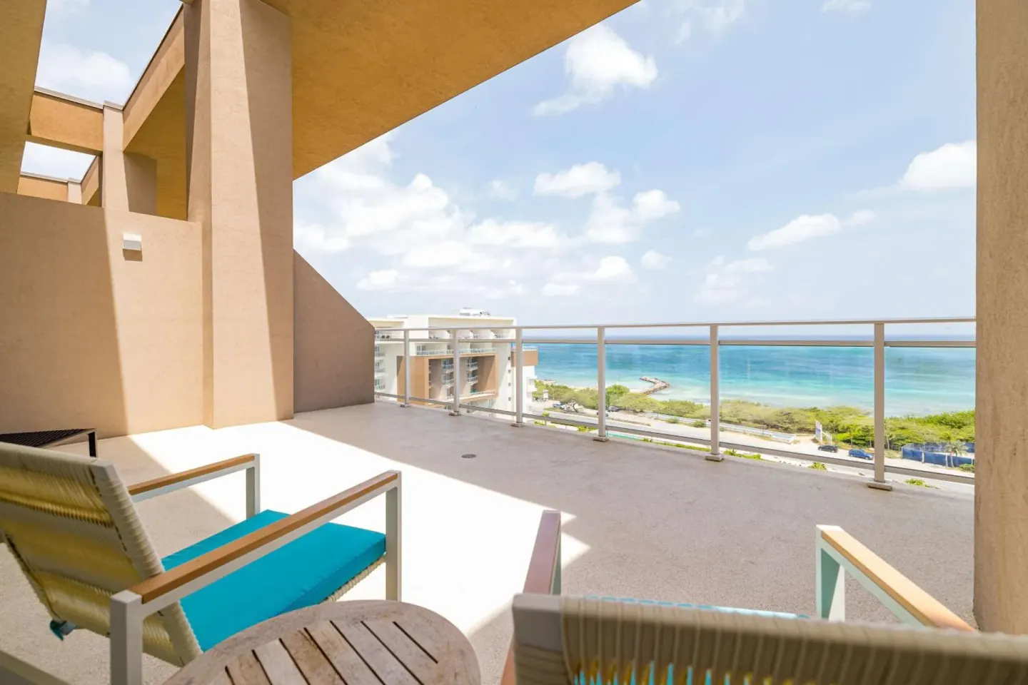 Private balcony seating with ocean view at Embassy Suites Aruba Beach Resort.