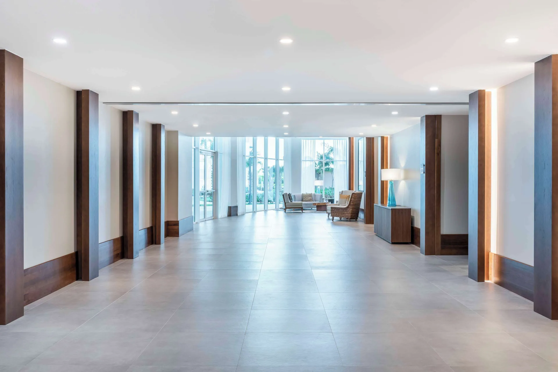 Bright corridor at Embassy Suites Aruba Beach Resort with tile floors and seating near windows.