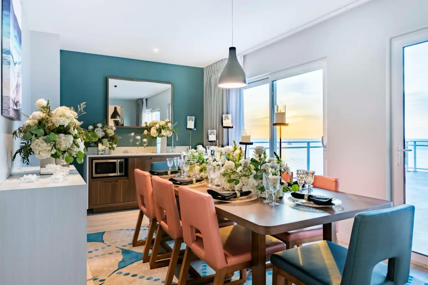 Suite dining table set with flowers by ocean-facing doors at Embassy Suites Aruba Beach Resort.