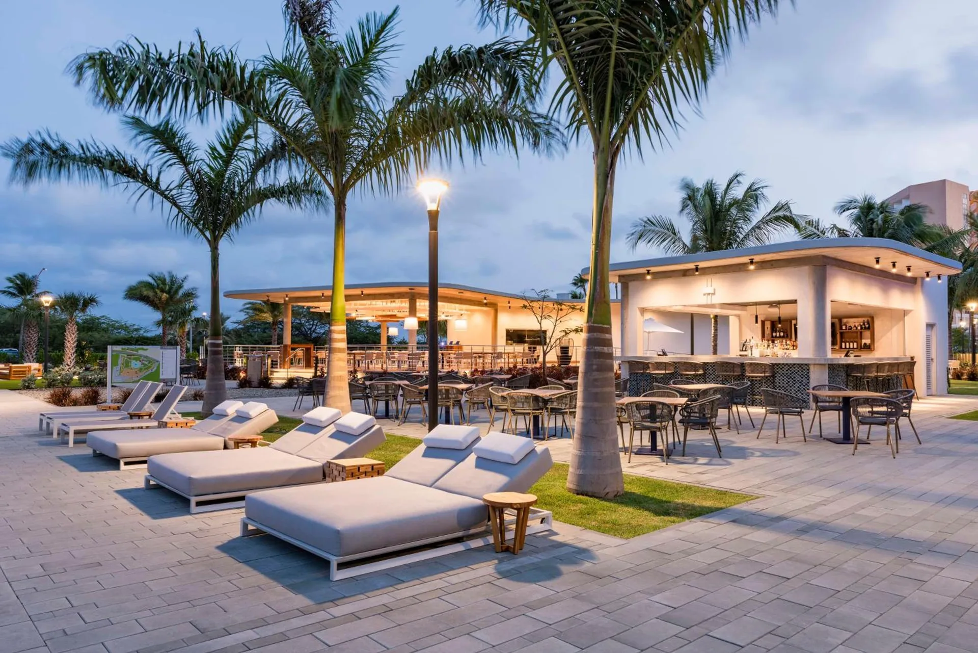 Poolside bar terrace with loungers and palm trees at Embassy Suites Aruba Beach Resort.